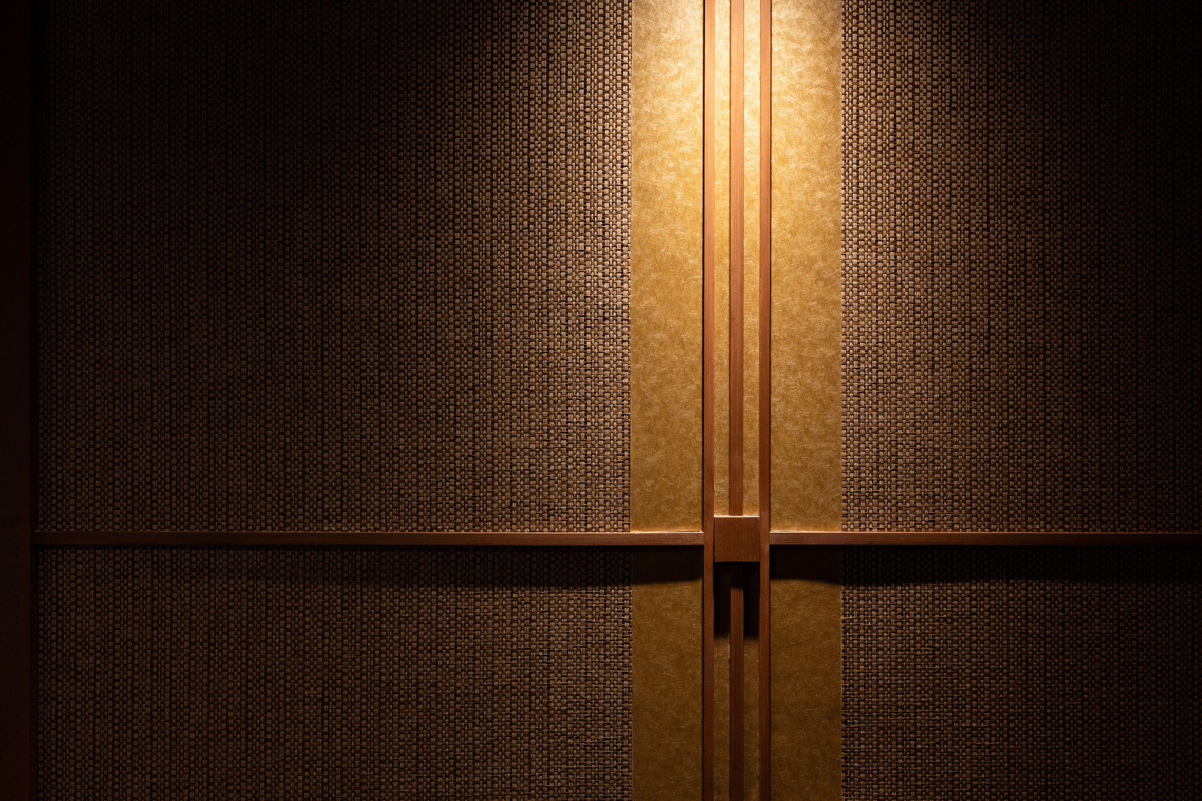 Pared con un patrón texturizado y un panel de madera en el centro.