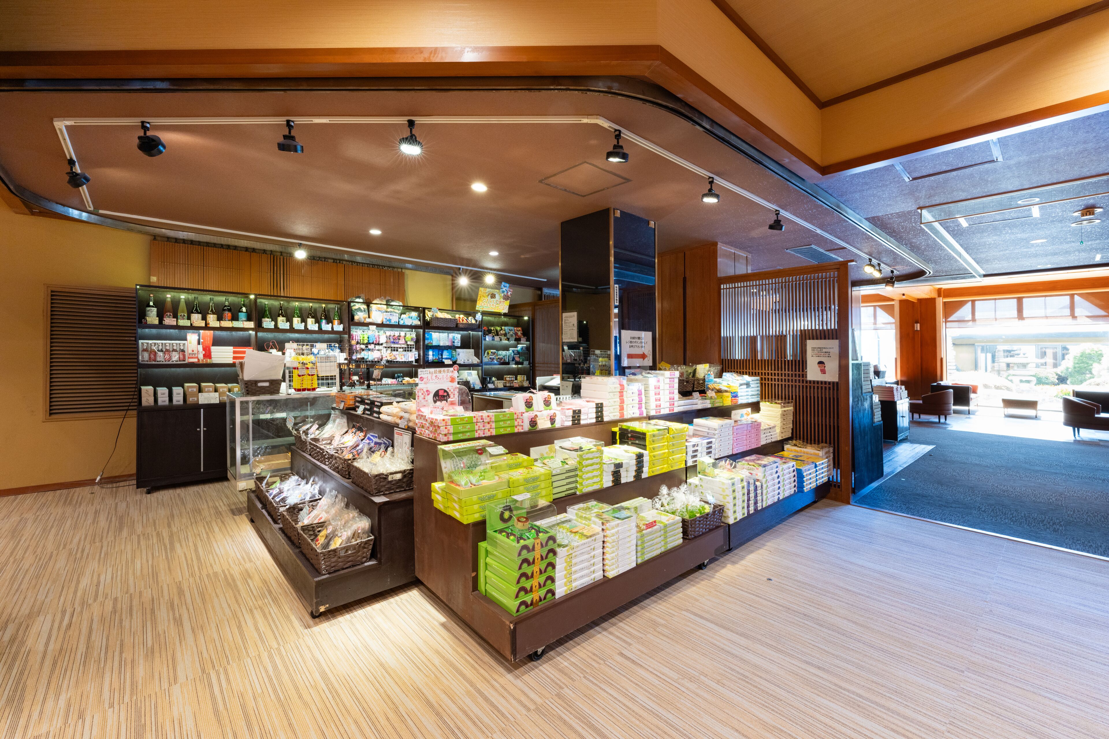 A well-lit store with various products on shelves and counters, a seating area with tables and chairs, and a visible entrance.