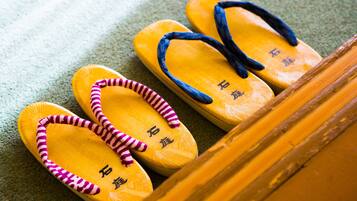 A pair of yellow flip-flops with blue straps and pink trim, placed on a textured surface.