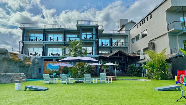 A multi-story hotel with outdoor seating and a mural. - Palau Central Hotel (Koror)