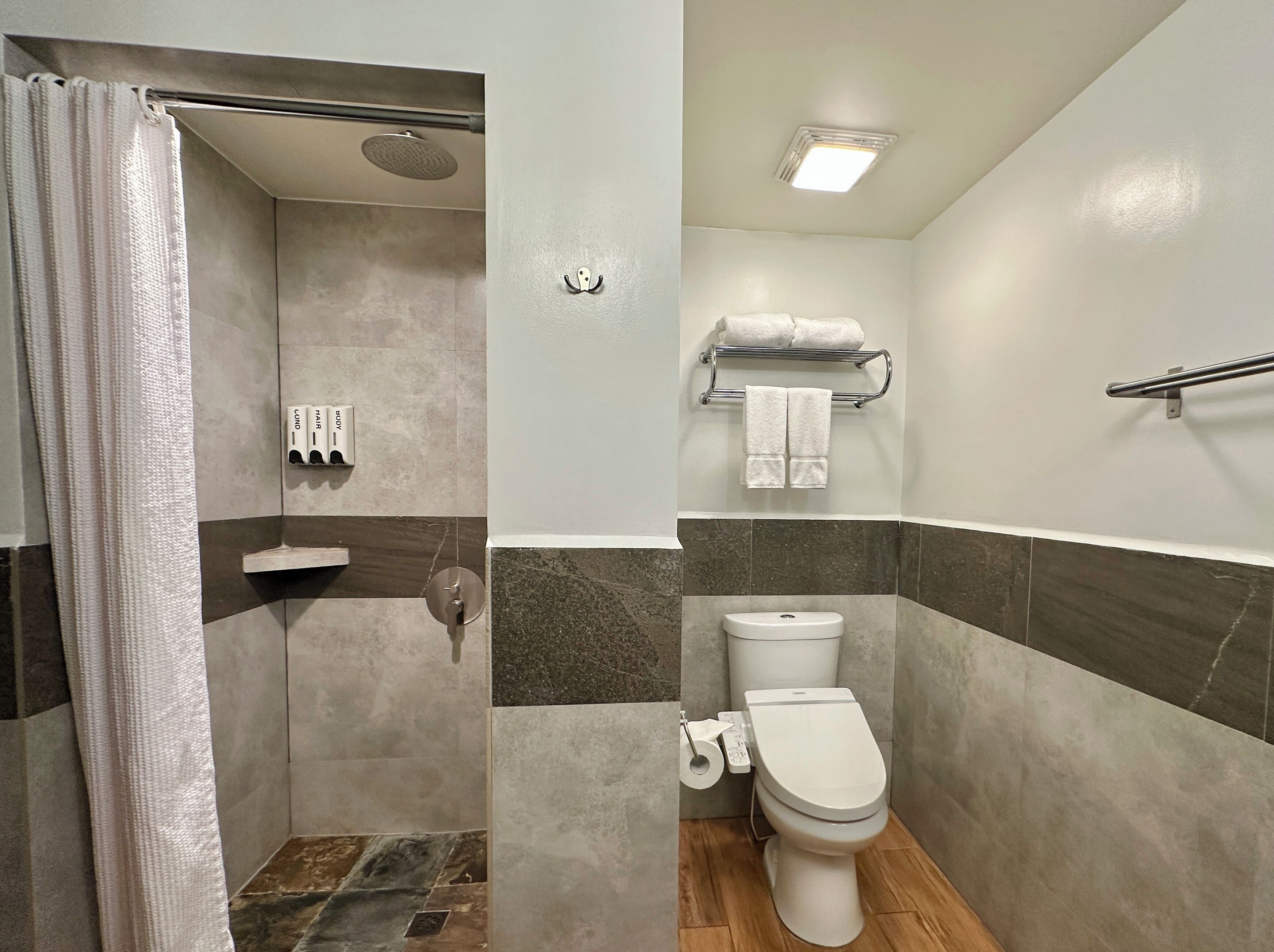 Ein Badezimmer mit Dusche, Toilette und Handtuchhalter.