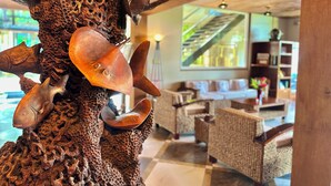 A sculpture of a sea creature with multiple horns and a shell, set against a backdrop of a modern interior with wicker furniture and a staircase. - Palau Central Hotel (Koror)