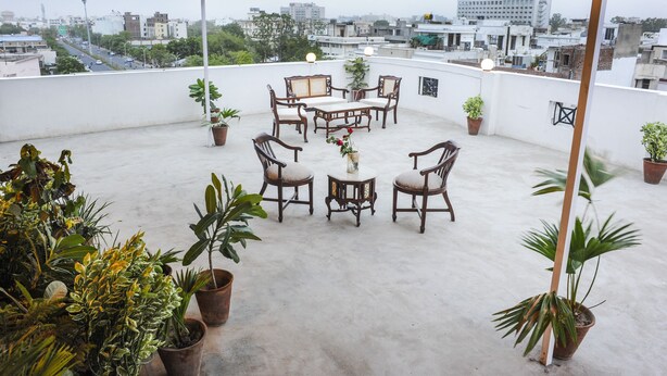 Terraza en la azotea con mesa y sillas, rodeada de plantas en macetas.