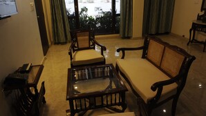 Una sala de estar con un sofá, sillones, una mesa de centro y un televisor en la pared.