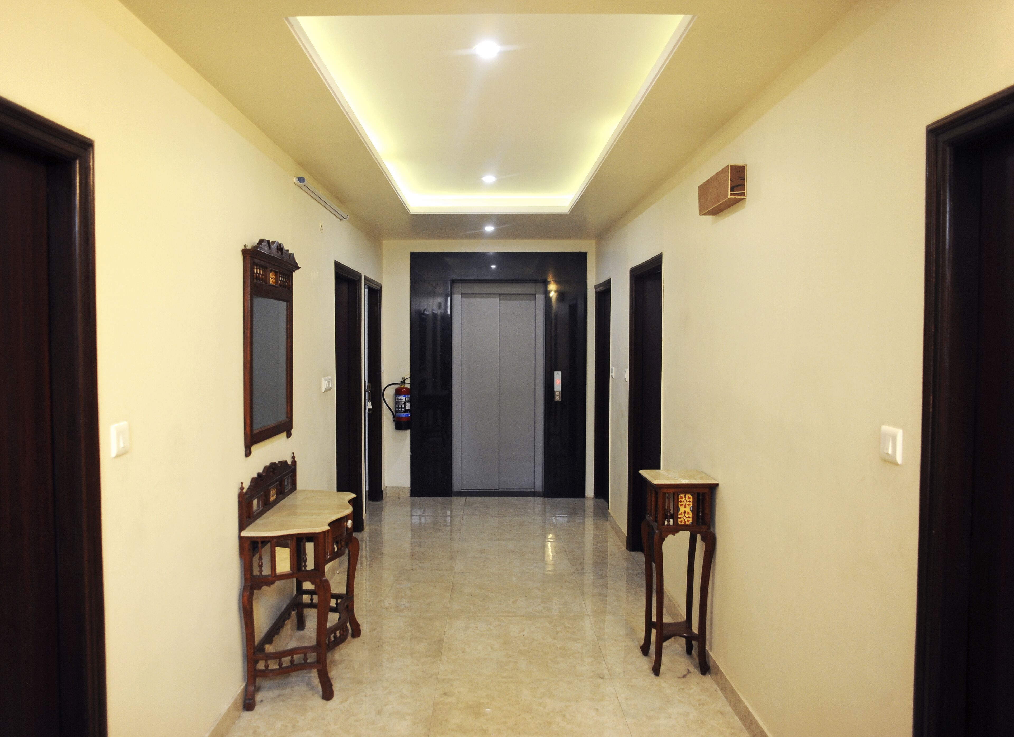A hallway with a ceiling light, a fire extinguisher, and a door at the end.