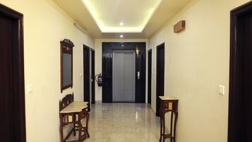 A hallway with a ceiling light, a fire extinguisher, and a door at the end.