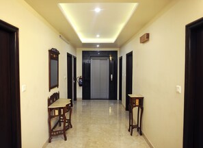 A hallway with a ceiling light, a fire extinguisher, and a door at the end.