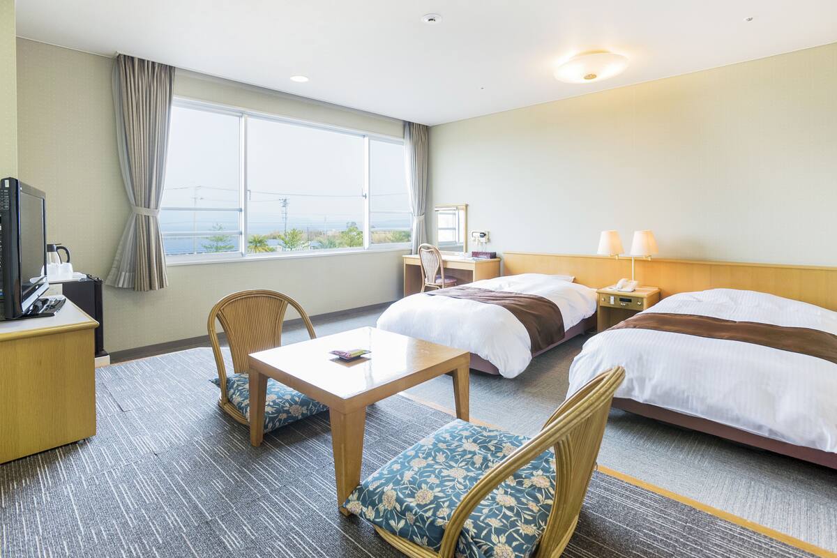 Hotelkamer met een bed, een bureau, een stoel, een tafel, een nachtkastje, een lamp en een raam met uitzicht.