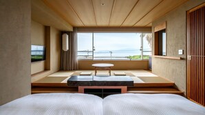 Een moderne hotelkamer met een groot bed, een klein tafeltje en uitzicht op zee.