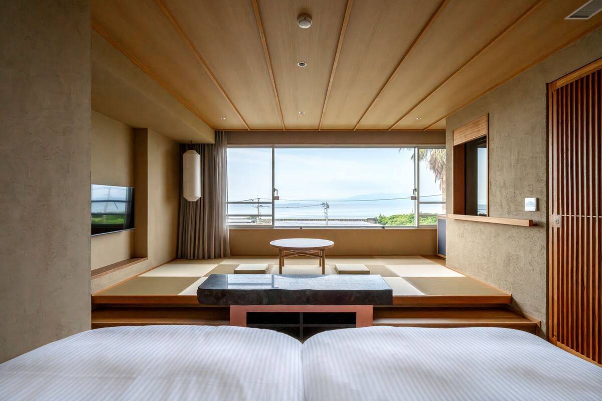 Een moderne hotelkamer met een groot bed, een klein tafeltje en uitzicht op zee.