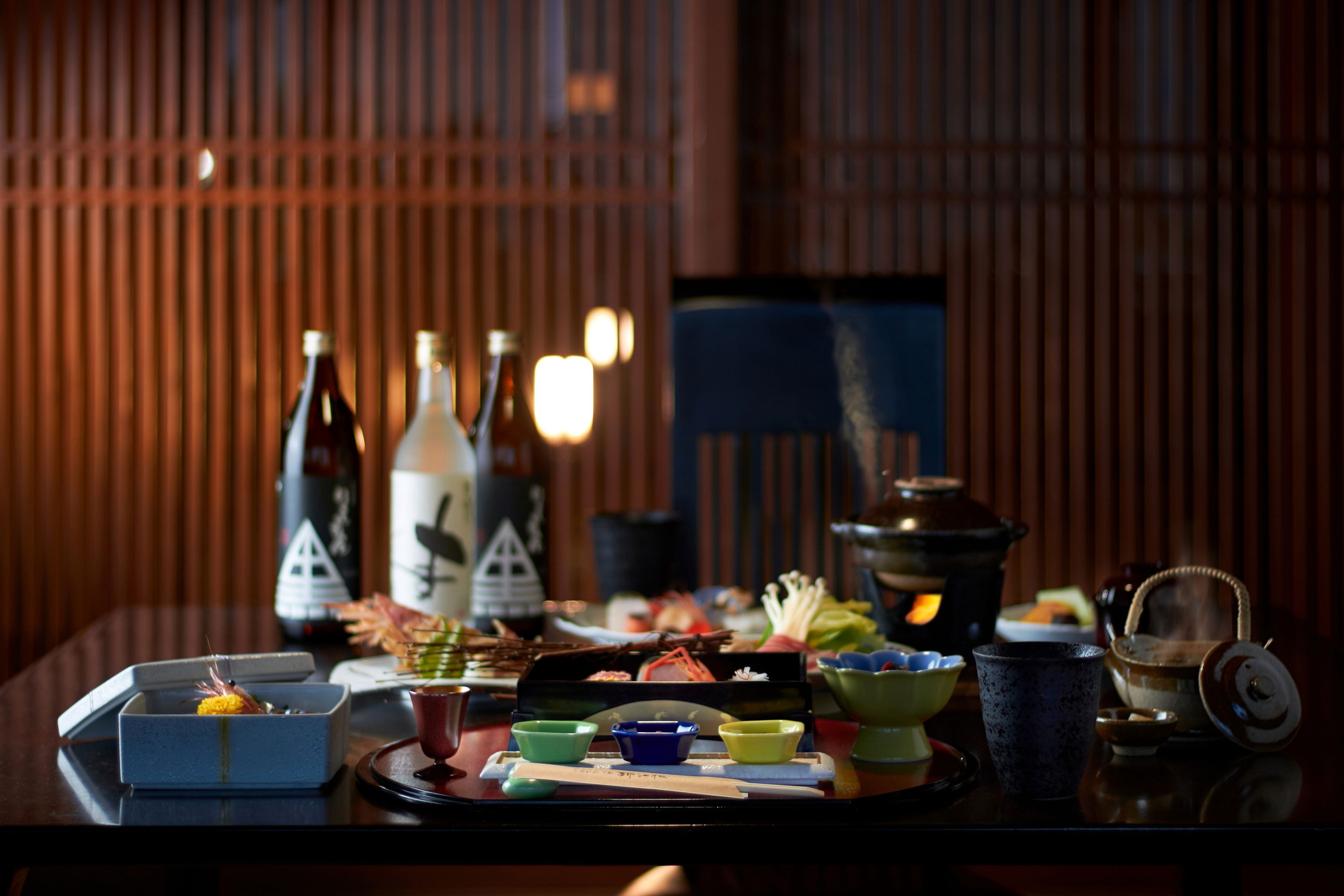 A dining table with various dishes, bottles, and a teapot.