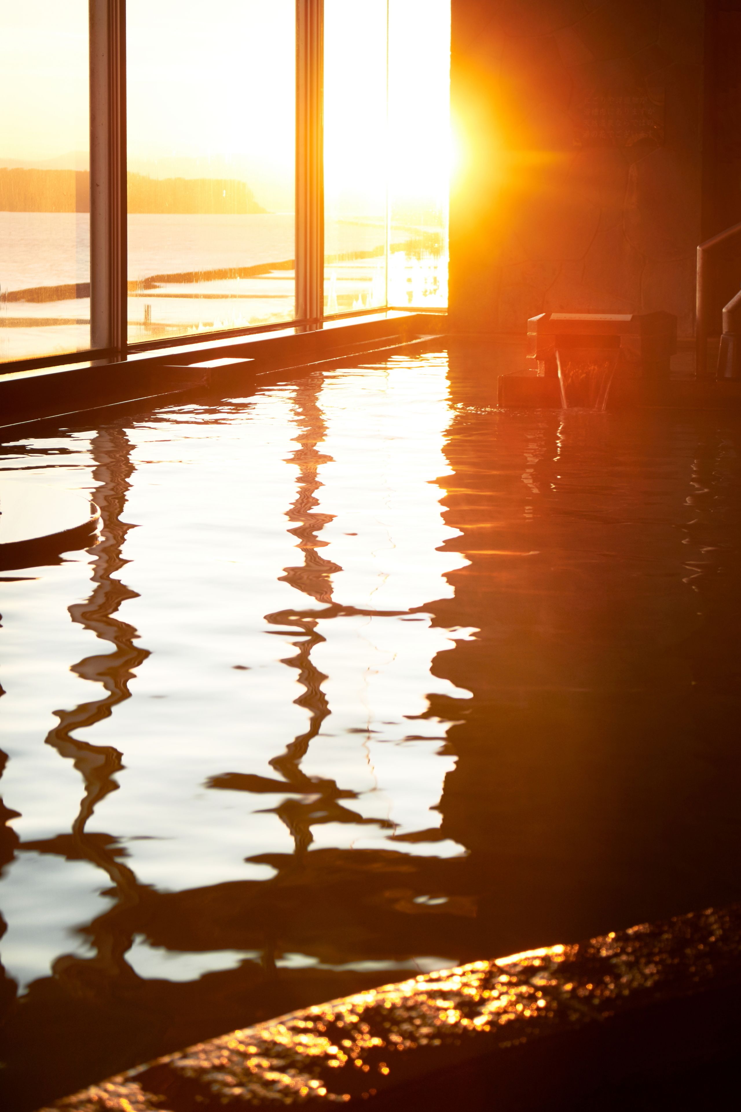 Piscina com vista para o pôr do sol através de amplas janelas.