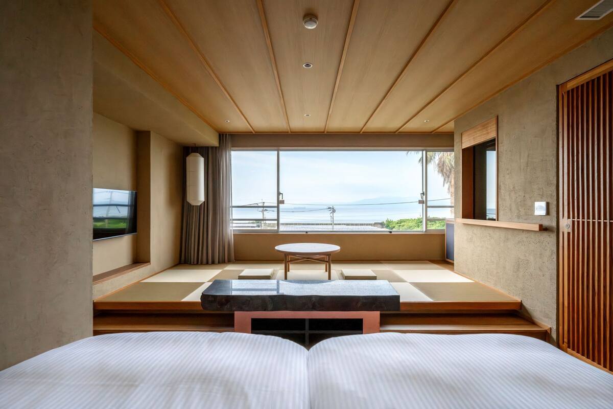 Een moderne kamer met een bed, een klein tafeltje, uitzicht op zee en een schuifdeur.