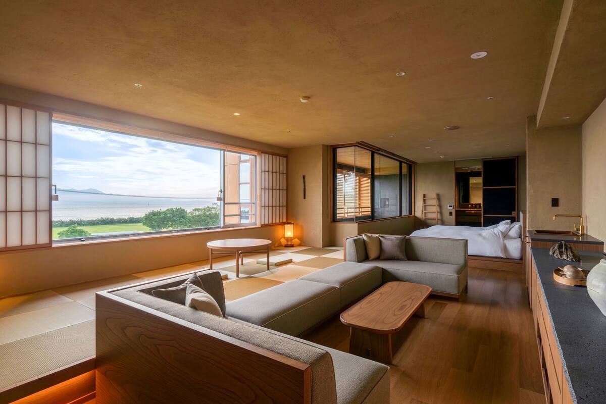 Een moderne hotelkamer met een groot raam, een bank, een klein tafeltje en een bed.