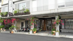 A hotel with a covered entrance, potted plants, and a scooter parked outside.
