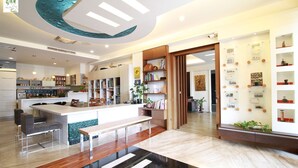 A modern kitchen with a central island, bar stools, and a dining area with a black and white floor pattern.