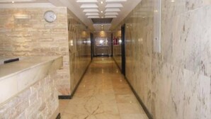 Eine Hotelhalle mit Marmorboden, einer Rezeption und einer Uhr an der Wand.