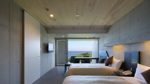 A modern hotel room with two beds, a small table, and a view of the sea. - The Hotel Yakushima (Yakushima)