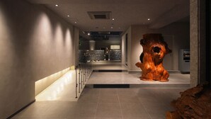 A modern interior with a central wooden sculpture, a staircase, and a stone wall in the background. - The Hotel Yakushima (Yakushima)