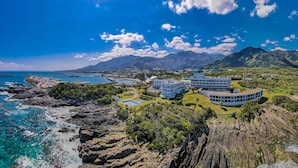 A coastal resort with a circular building surrounded by lush greenery and rocky terrain. - The Hotel Yakushima (Yakushima)