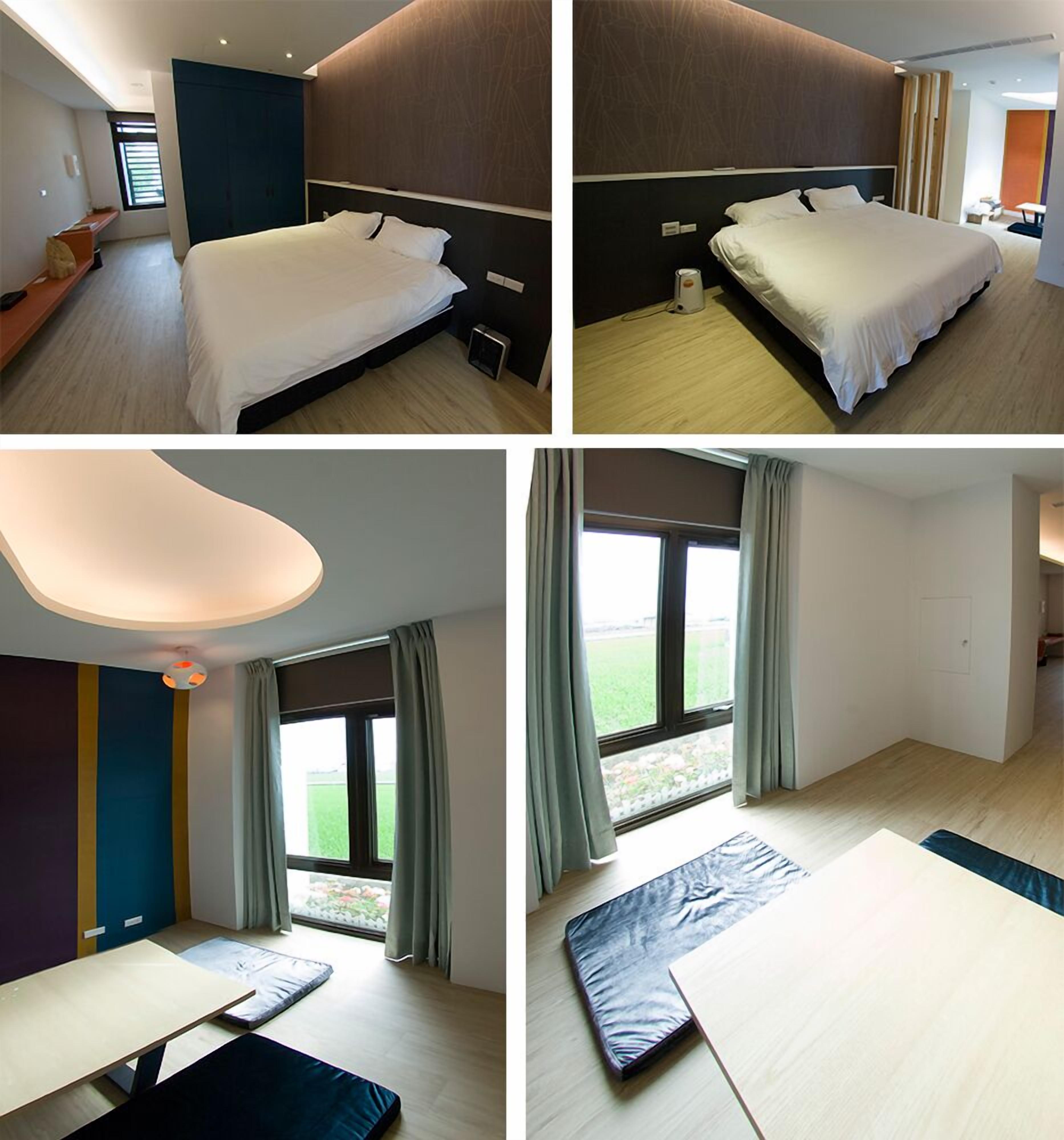 Quarto de hotel com cama, escrivaninha, cadeira e janela com cortinas.