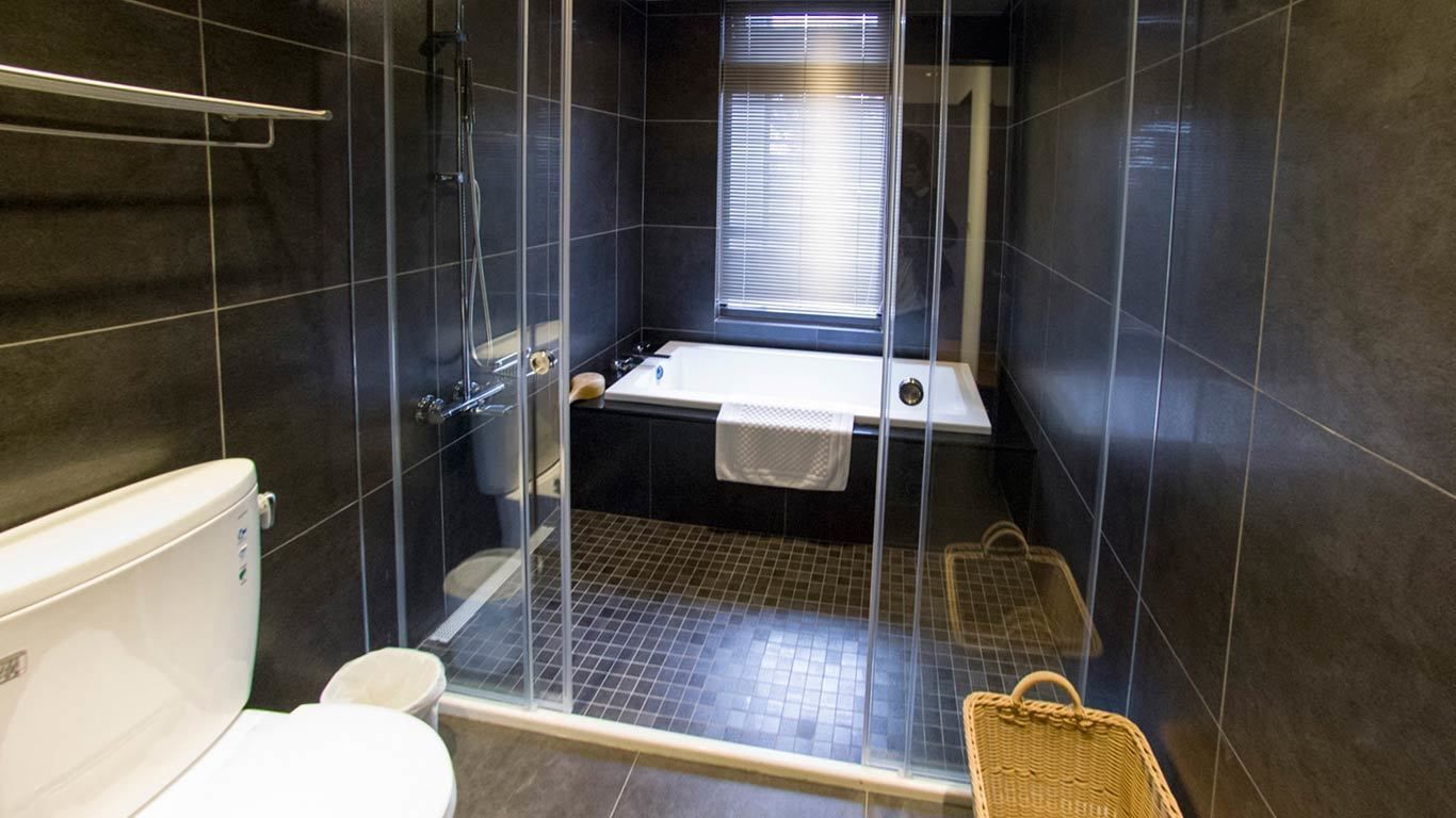 Een moderne badkamer met een glazen douchecabine, een wit bad en een toilet.