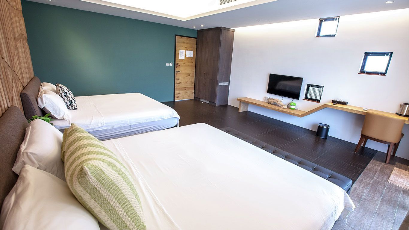 Una habitación de hotel con dos camas, televisión, escritorio y una silla.