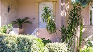 A building entrance with a stone wall, a white door, and various potted plants.