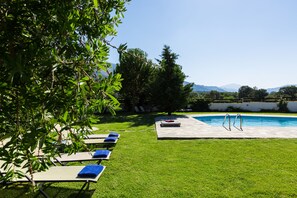 A pool area with lounge chairs and a pool.