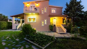 A modern two-story house with a covered porch, a staircase leading to the entrance, and a well-maintained garden.