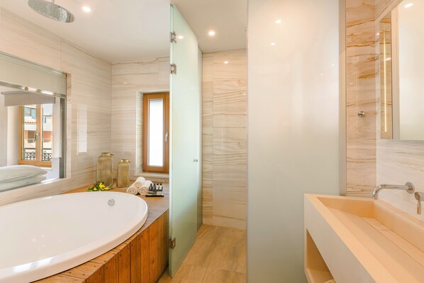 Un baño moderno con una bañera independiente grande, un tocador separado con lavabo y una zona de ducha con mampara de vidrio.