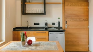 Een kleine keuken met een houten deur, een inbouwplank met glaswerk, een koffieapparaat en een vaatwasser.