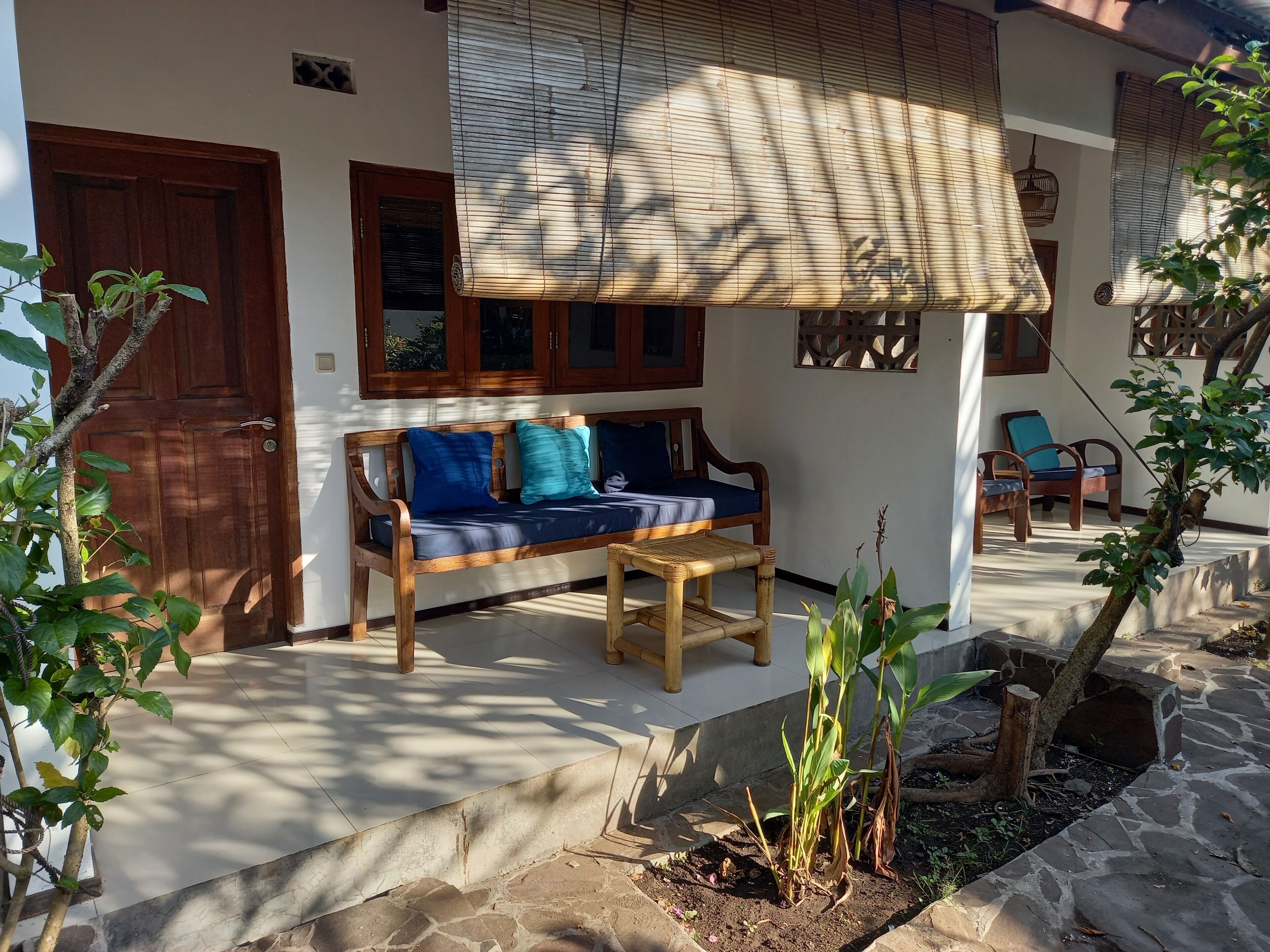 A wooden bench with cushions, a door, and a window with blinds.