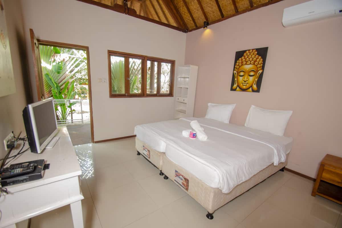 A bedroom with a bed, a desk with a computer, a window with blinds, and a Buddha painting on the wall.