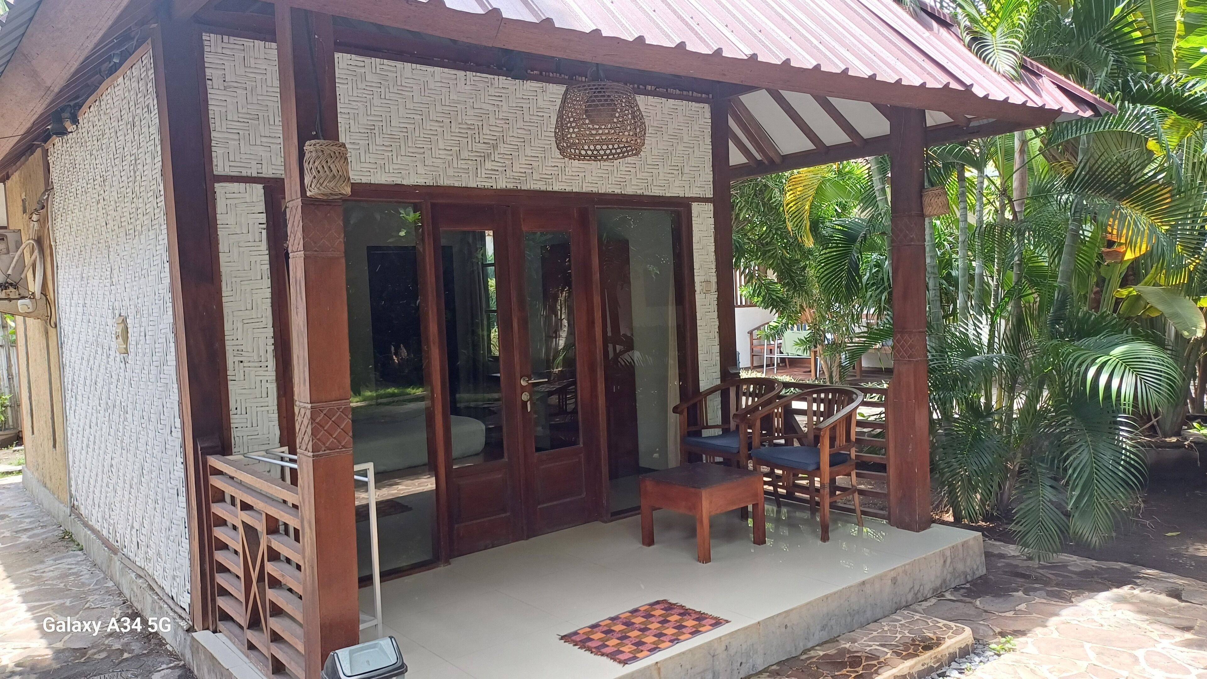 A small, rustic building with a wooden exterior, large glass doors, and a covered porch with wooden furniture.