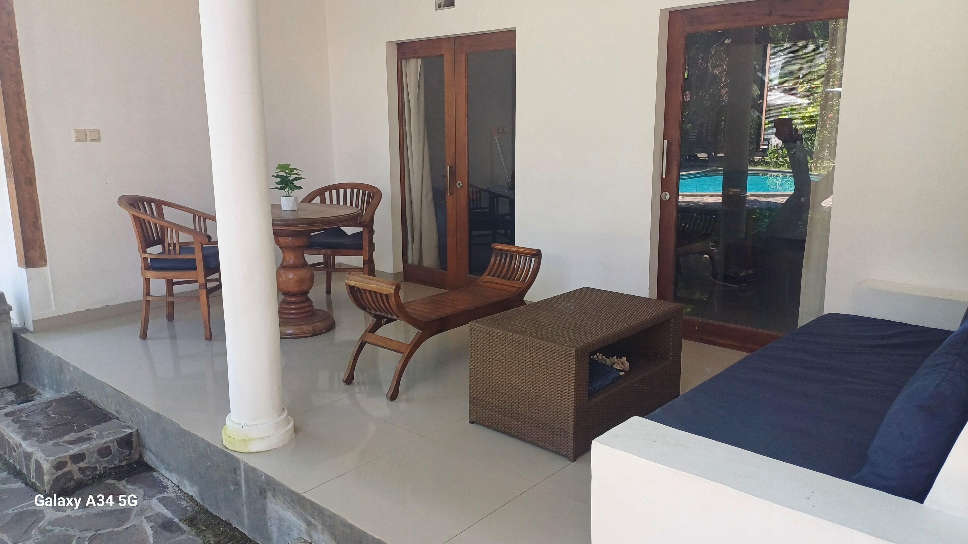 A covered outdoor seating area with a dining table, chairs, and a sofa.