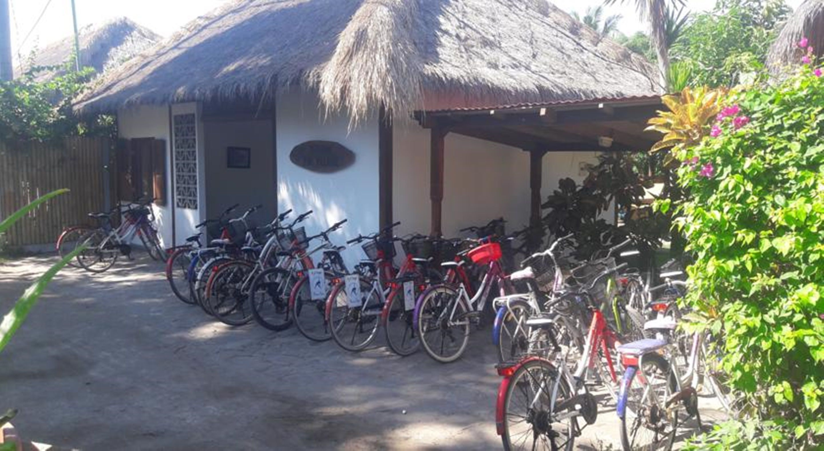 A building with a thatched roof and a covered porch. Several bicycles are parked in front.