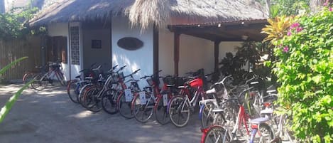 A building with a thatched roof and a covered porch. Several bicycles are parked in front.