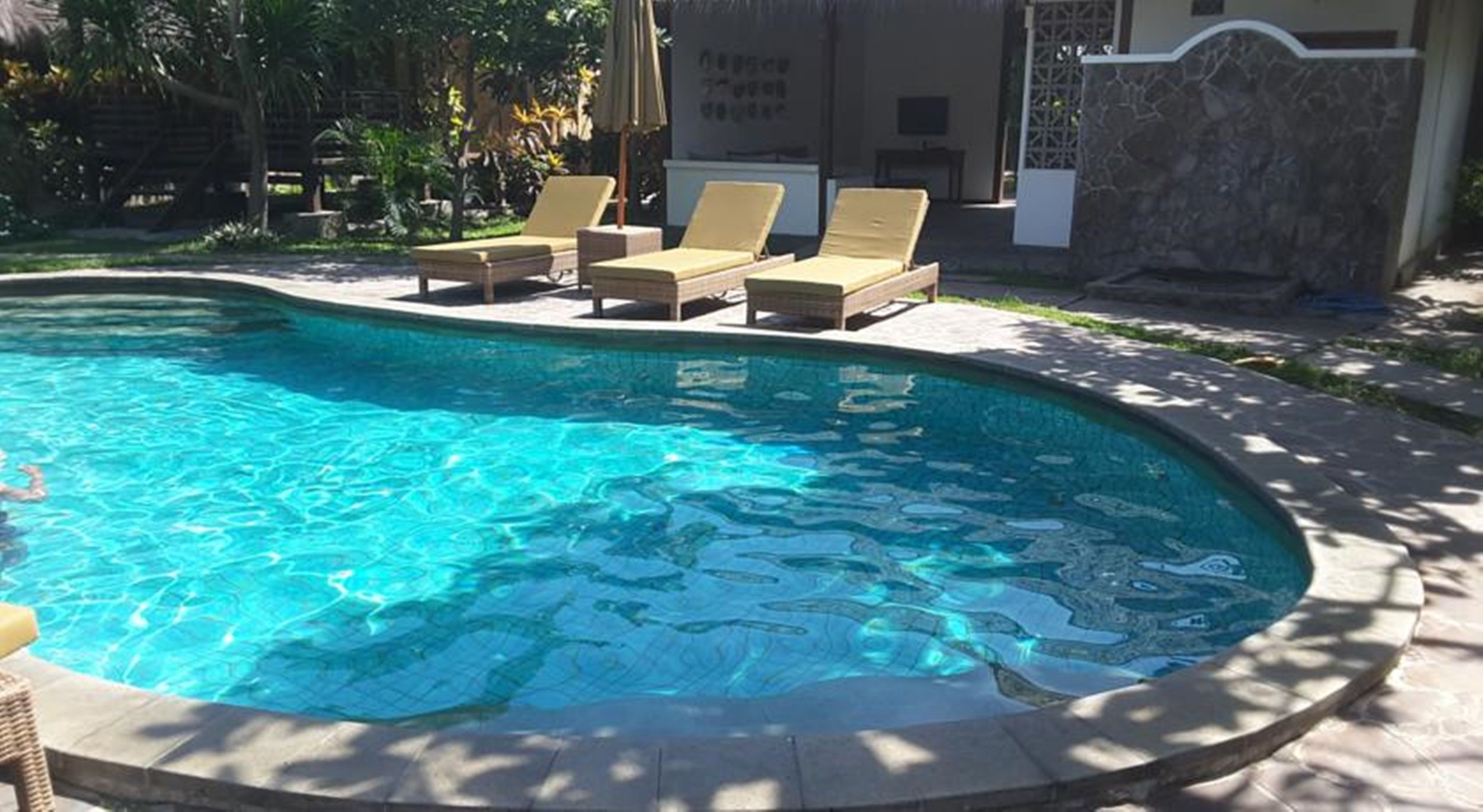 A swimming pool with lounge chairs and a stone wall.