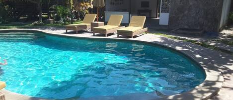 A swimming pool with lounge chairs and a stone wall.