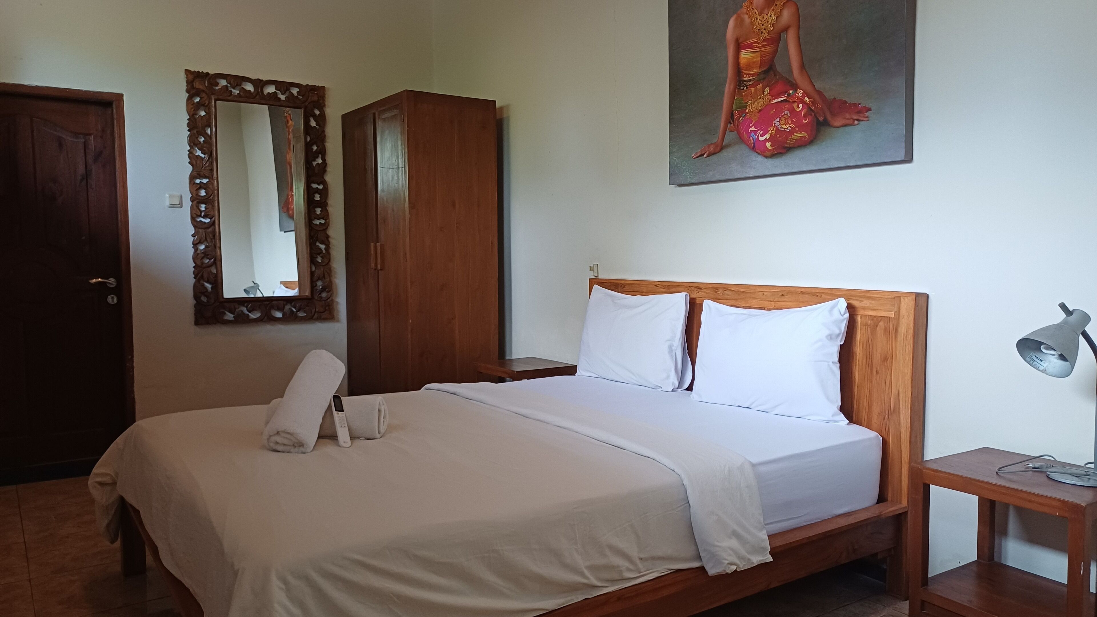 A neatly made bed with white linens, a wooden headboard, and two bedside tables with lamps.