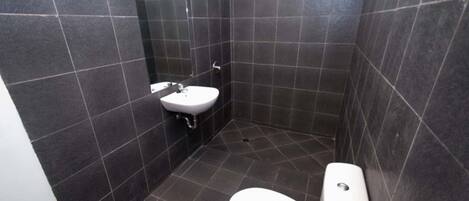A small, dark-tiled bathroom with a white sink and toilet.