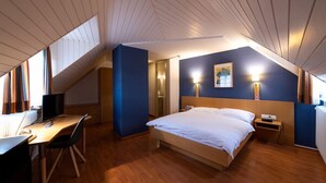 A bedroom with a bed, bedside table, and a desk with a chair. - Hotel Restaurant Les Négociants (Vevey)