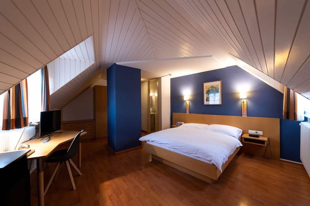 Ein Schlafzimmer mit Bett, Nachttisch und Schreibtisch mit Stuhl.