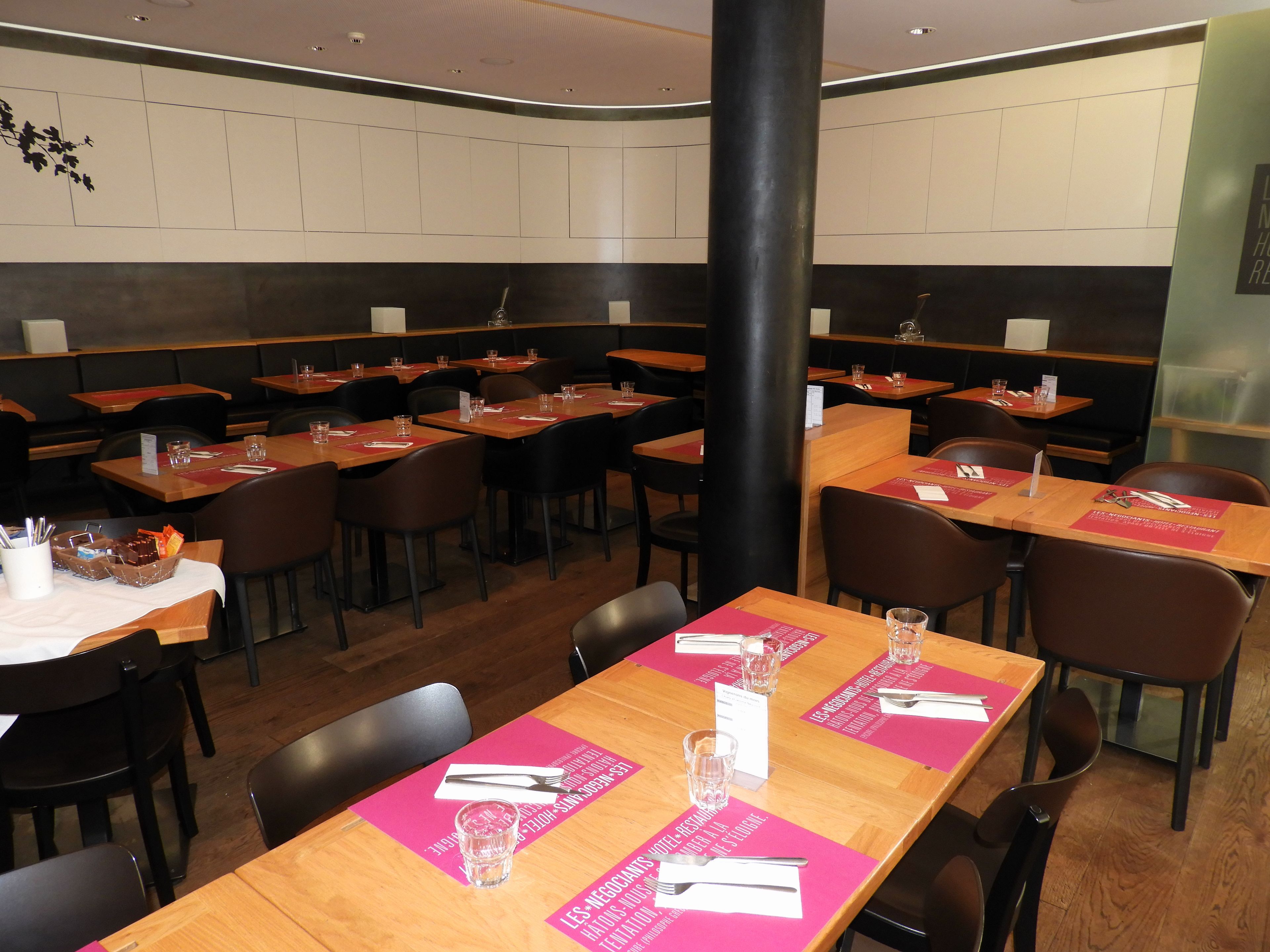 Un restaurante con mesas de madera y sillas negras, dispuesto en un espacio amplio.