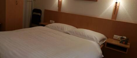 A hotel room with a large bed, two bedside lamps, a nightstand, and a framed picture on the wall.