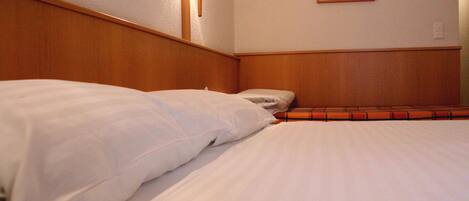 Una habitación de hotel con cabecera de madera, cama con ropa de cama blanca, lámpara de pared y una obra de arte enmarcada.