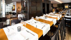 A restaurant with multiple dining tables set for guests, featuring white tablecloths and wooden accents. - Hotel Restaurant Les Négociants (Vevey)