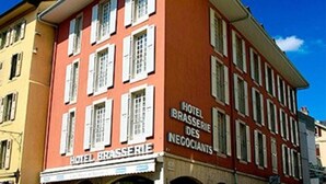 A red building with a sign reading "Hotel Brasserie Des Négociants" and a visible entrance with outdoor seating. - Hotel Restaurant Les Négociants (Vevey)