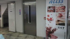 A hallway with an elevator, a door with a digital display, and a poster advertising 'aliss Wellness & Spa'. - Derpa Suite Hotel Osmanbey (Istanbul)